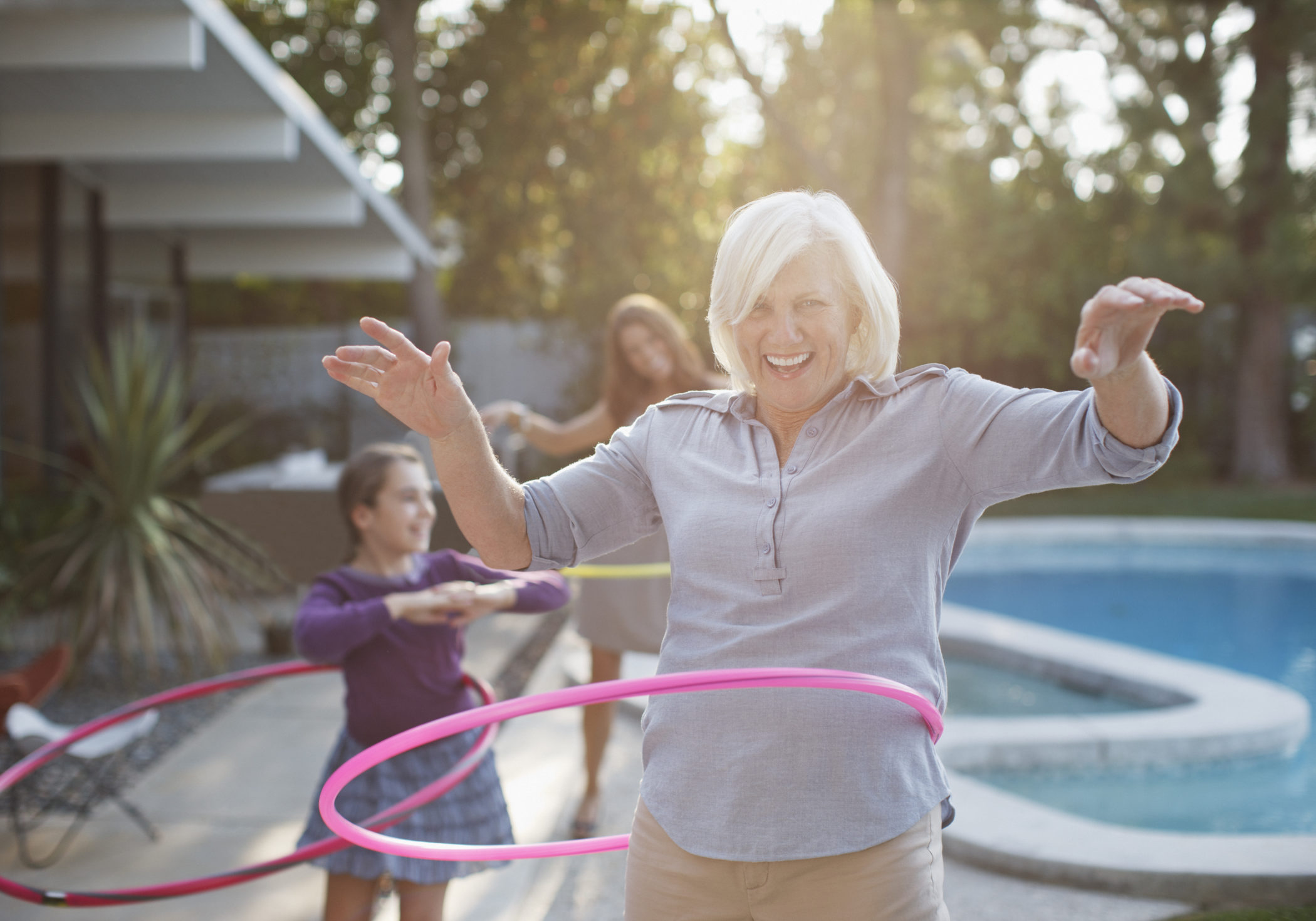 Older woman hula hooping in backyard